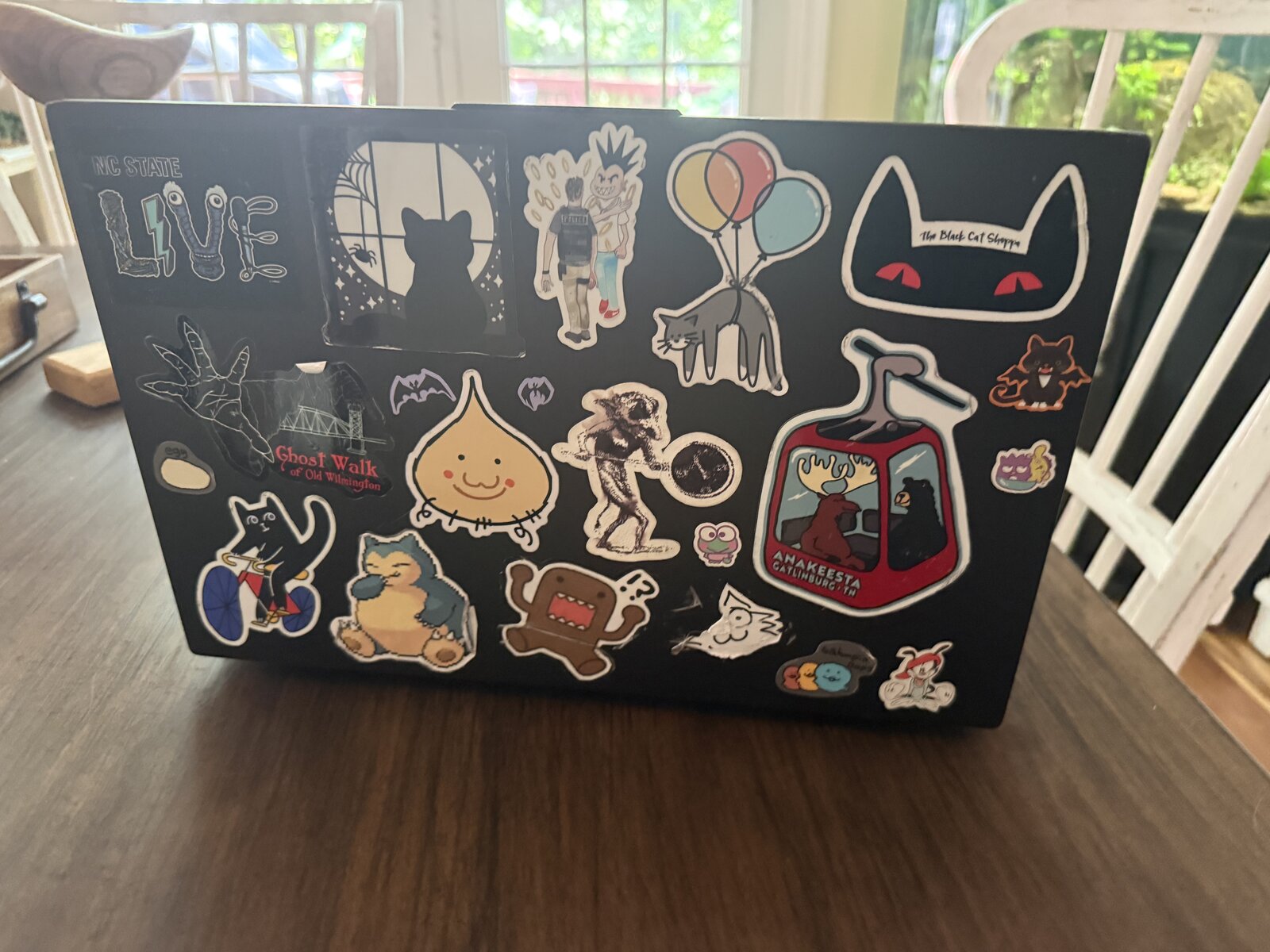 A black laptop covered in about 20 custom StyckLizardz die-cut decals